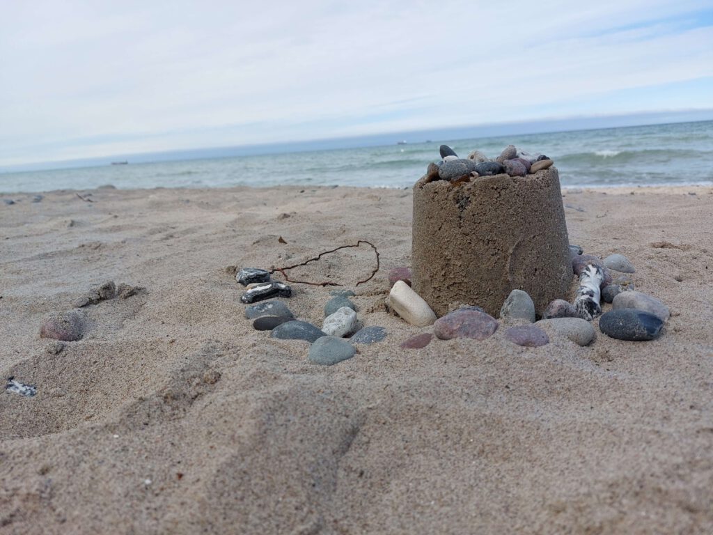 kleine Sandburg mit Steinen am Strand